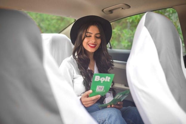 A portrait of a woman reading a community newsletter in a car.